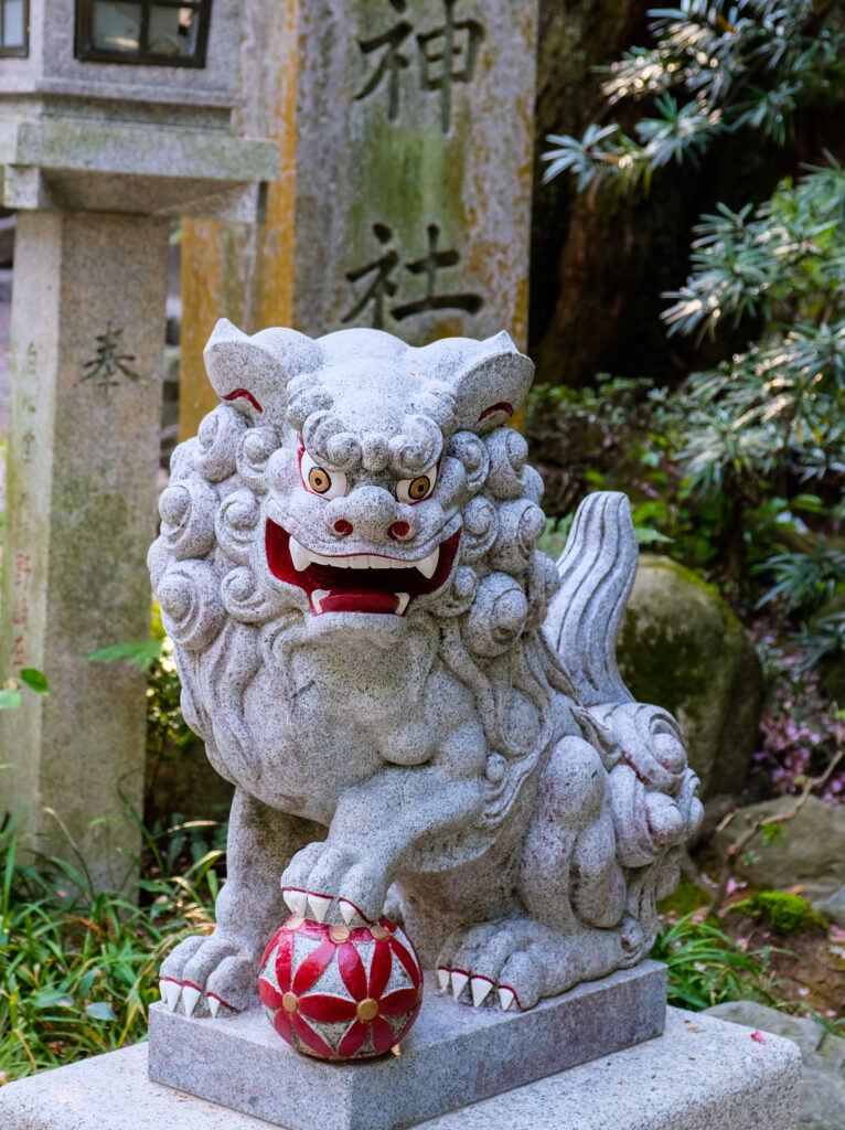 A stone sculpture with the eyes, mouth, and claws painted, along with the ball the statue has under one paw.