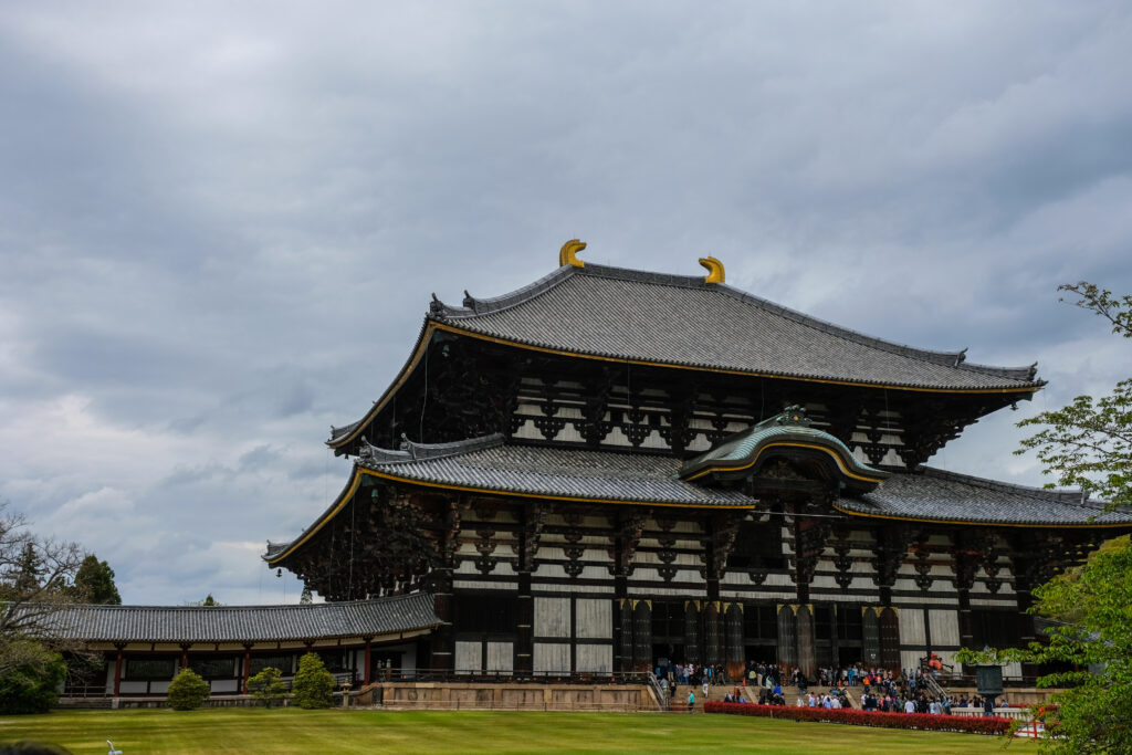 The largest wooden structure in the world, the Todaiji Temple. Small figures can be seen entering the large doors in front, giving a sense of scale to the image.
