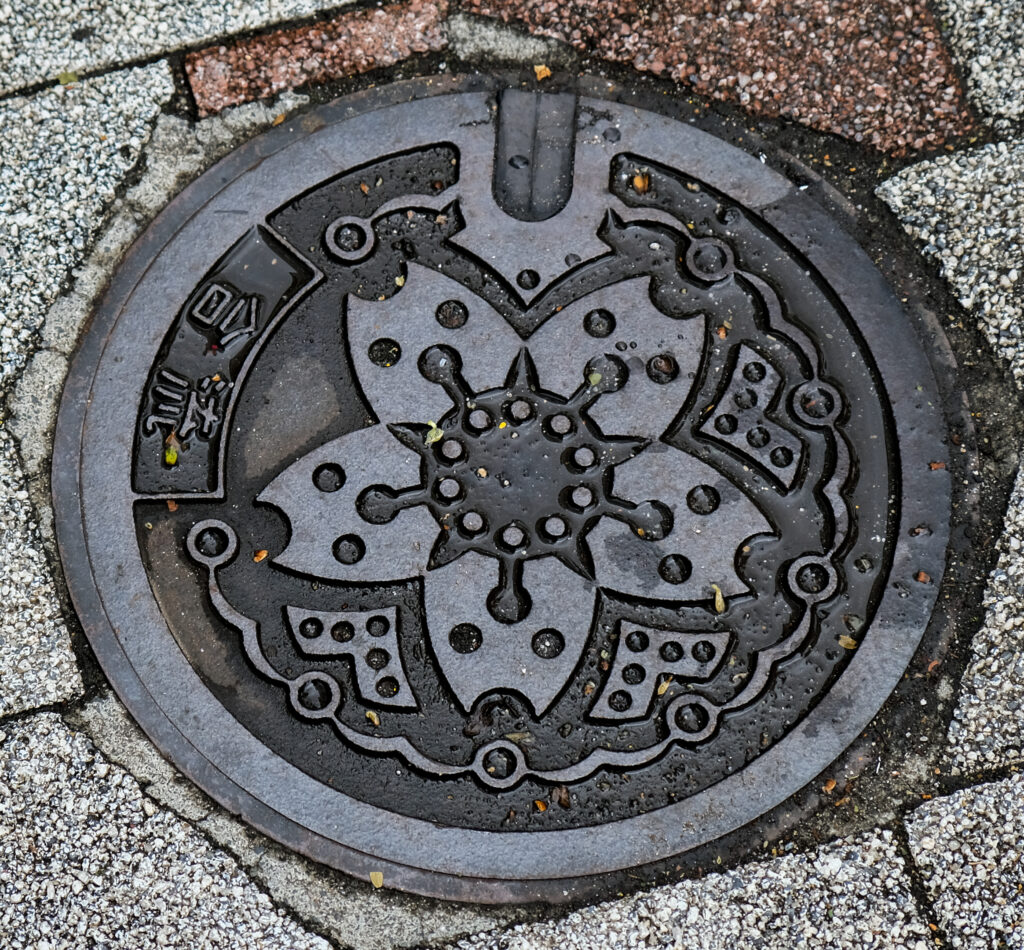 An ornate manhole cover with a large sakura blossom embossed in the steel.