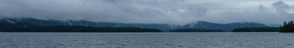 A cloudy day at Squam, looking across the lake at the fog and mists covering the hills.